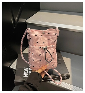 Detail shot of pink quilted bubble fabric mini crossbody bag with black bunny pattern