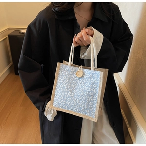 Detail of floral linen lunch bag featuring white rope handle and large wooden button