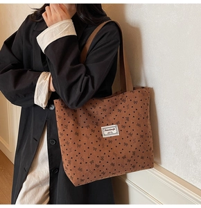 Détail du sac fourre-tout en velours côtelé marron avec motifs de cœurs et nœuds noirs