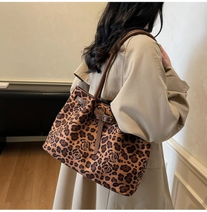 Detailed shoulder view of a large leopard print tote bag with brown leather handles