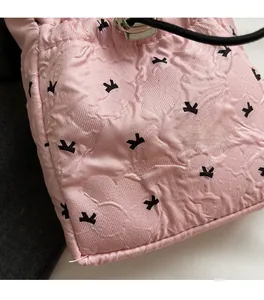 Close-up of pink quilted drawstring bag featuring black bow patterns and silver clasp