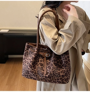 Detail showing large leopard and rose print tote bag with brown leather handles and buckle