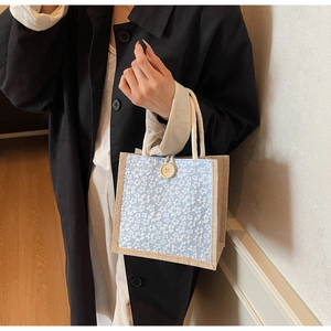 Close-up of linen lunch bag featuring blue floral lace details and rustic wooden button