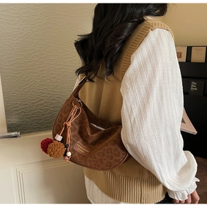 Détail du sac hobo léopard avec breloque boule en peluche et étiquette de marque