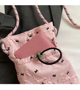 Pink pleated crossbody bag with black bow print showing front pocket storage detail