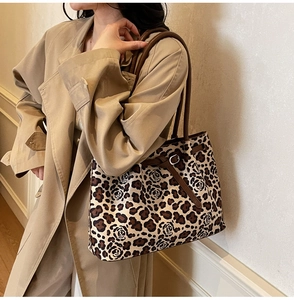 Detail of leopard print tote bag with brown leather straps worn on shoulder with khaki coat