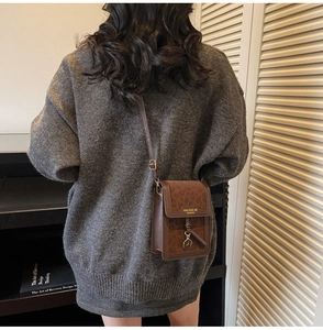 Detail of a brown leopard print crossbody bag featuring a golden round metal charm