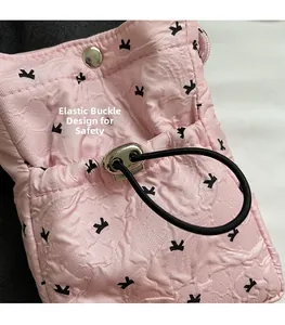 Pink textured phone bag with bird patterns, featuring a functional drawstring closure
