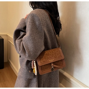 Détail du sac léopard avec breloque en perles et logo sur un manteau en laine