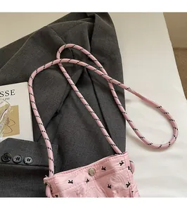Detailed close-up of pink ruched crossbody bag with woven rope strap and metal buckle