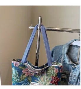 Detail of floral embroidery and sturdy woven handle on this large canvas tote bag