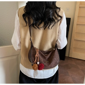 Détail du sac demi-lune léopard avec pompon bordeaux et pendentif en damier noir et blanc