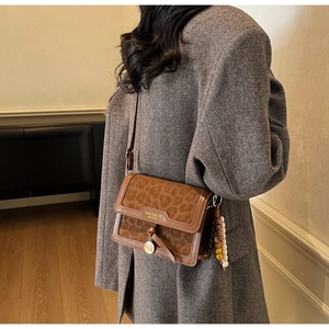 Détail du sac bandoulière léopard avec bordure en cuir et breloque en perles colorées