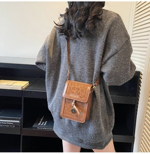 Close-up of leopard print crossbody bag with tassel detail on a grey sweater