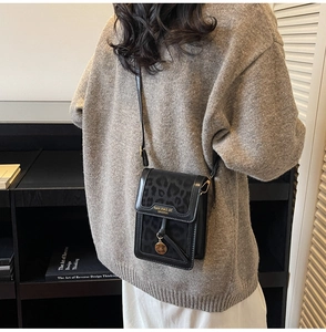 Detailed view of leopard print crossbody bag with gold pendant and brand lettering