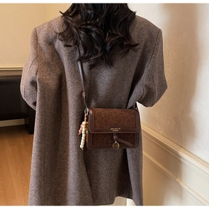 Détail d'un sac bandoulière à motif léopard marron avec breloque perlée sur un modèle