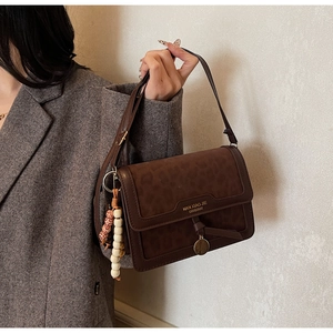 Détail d'un sac bandoulière vintage avec rabat motif léopard et breloque en perles