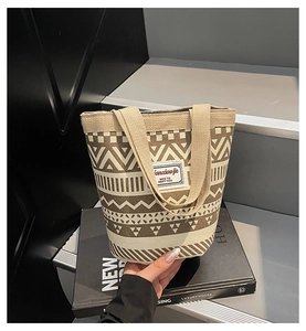 Detail of geometric canvas bucket bag with wide handle and woven textile label