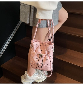 Detail of pink quilted handbag with black rabbit prints and woven rope strap