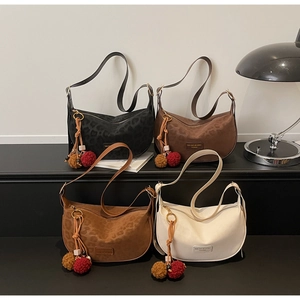 Détail de quatre sacs hobo en velours avec texture léopard et pompons décoratifs en fourrure