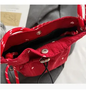 Close-up of red floral bag showing silver metal snap button and woven drawstring details