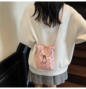 Detail of pink pleated crossbody phone bag with black cross patterns and drawstring pocket
