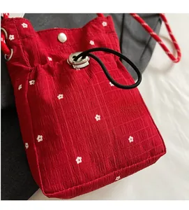 Detail of red floral drawstring crossbody bag with textured pleats and silver metal buckle