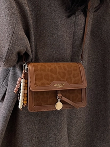Sac bandoulière marron à motif léopard avec boucle dorée et perles sur manteau gris