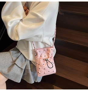 Detailed close-up of a pink quilted phone bag with butterfly print and drawstring pocket