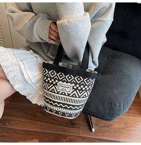 Detail of canvas bucket bag featuring ethnic geometric prints and black woven handles