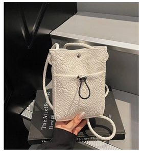 Detailed view of white woven crossbody phone bag with metal clasp and black tassel accent