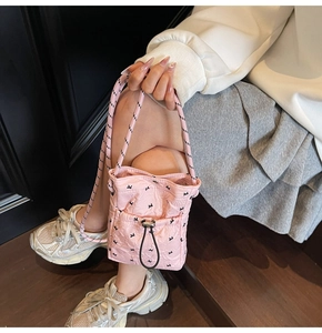 Detail shot of pink quilted crossbody bag with cute butterfly patterns and woven strap