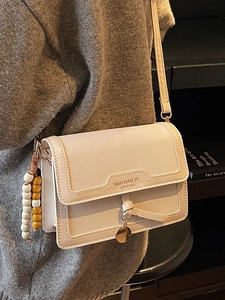Sac bandoulière chic en cuir crème avec rabat géométrique et breloque décorative