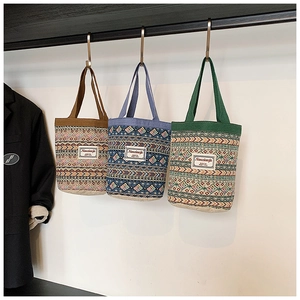 Gros plan de trois sacs seaux en lin tissé aux motifs ethniques sur des crochets