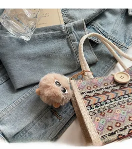 Detail of cute tan faux fur pompom charm with mini sunglasses on a woven tote bag