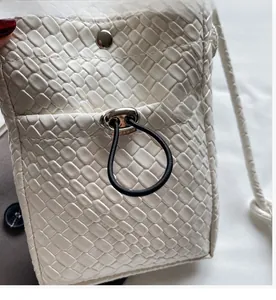 Close-up of woven white leather phone bag with silver magnetic clasp and drawstring closure