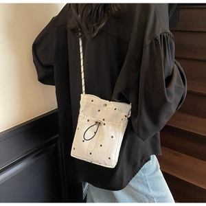 Close-up of white floral drawstring bag with mini black flower patterns on a model