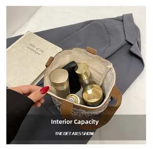 Vue de dessus montrant l'intérieur spacieux du sac seau tressé avec cosmétiques et mobile