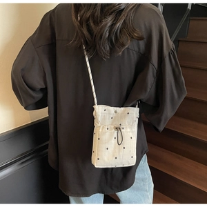 Detail shot of a white pleated crossbody bag with star patterns on a stylish woman