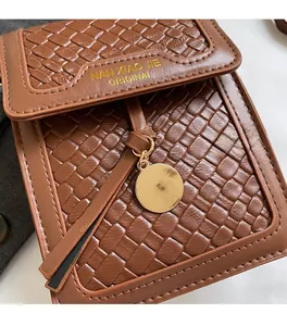 Close-up of brown woven leather texture with gold metal charm and branded logo detail