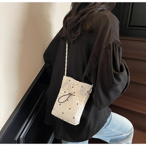 Detail of white floral crossbody bag with drawstring closure and woven rope strap