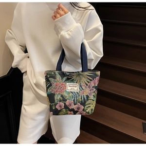 Detail of floral canvas tote bag with tropical leaf print and blue ribbon handles