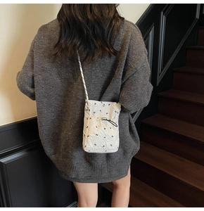 Detail of white quilted crossbody bag with black bunny prints and drawstring closure