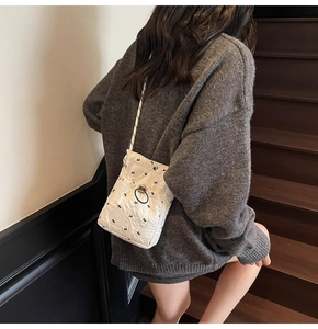Quilted white crossbody bag with black bunny embroidery shown on a model on stairs