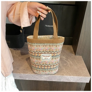 Détail du sac seau tissé avec motifs géométriques colorés et étiquette en tissu