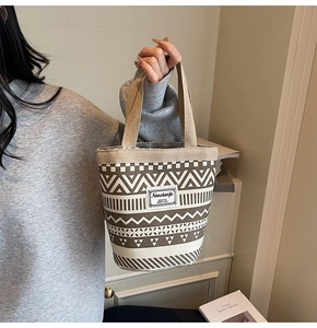 Detail of canvas tote bag with geometric patterns and reinforced handle in home setting
