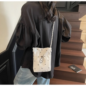Mini floral canvas crossbody bag with drawstring closure shown on model during use