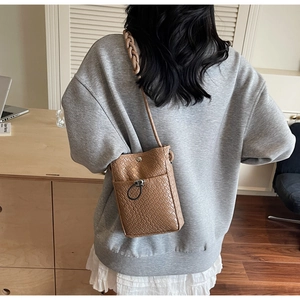 Detailed view of brown woven texture mini crossbody phone bag with metal clasp and strap