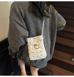Detailed back view of a white quilted crossbody bag with black rabbit patterns