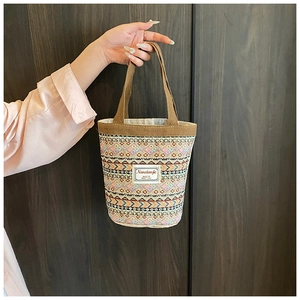 Détail d'un sac seau en lin aux motifs ethniques colorés avec une poignée marron